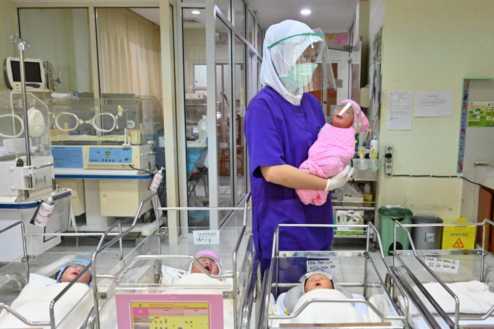 A nurse holds a newborn baby at a maternity facility in Jakarta, Indonesia, on April 21, 2020. By photographer Adek Berry / AFP