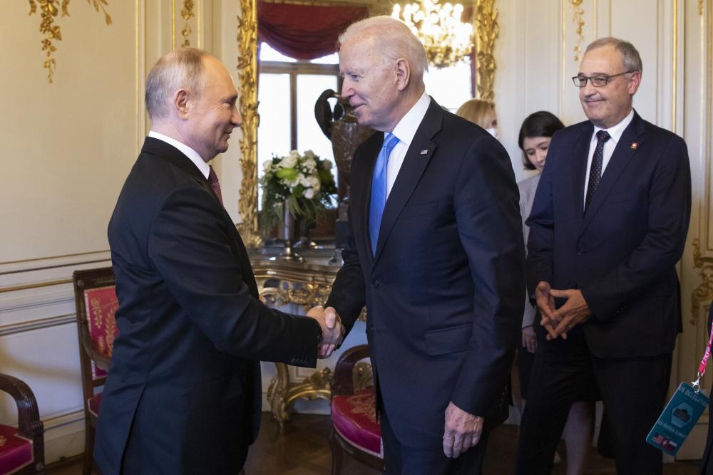 Russian president Vladimir Putin (left) shakes hands with US president Joe Biden (right) next to Swiss Federal president Guy Parmelin (back), during the US - Russia summit, on 16 June 2021